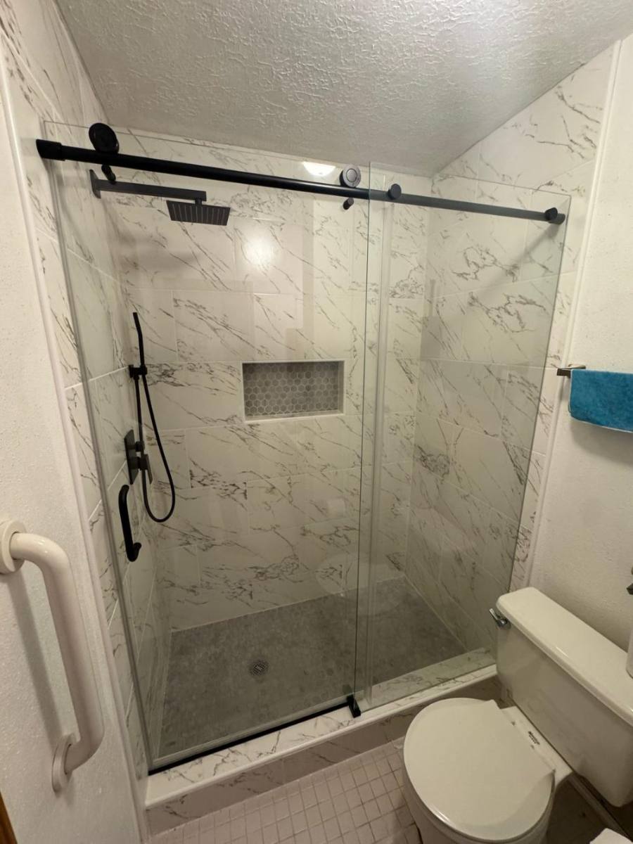 Finished bathroom with marble-look tile and a frameless glass shower