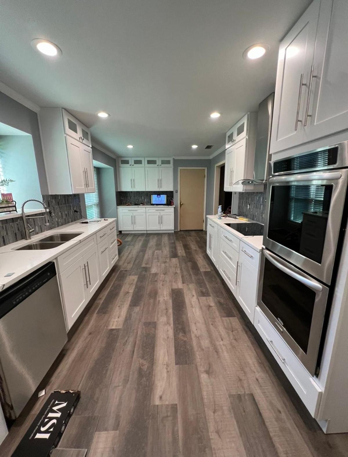 Finished kitchen remodel with white cabinets, quartz counters and wood-look flooring