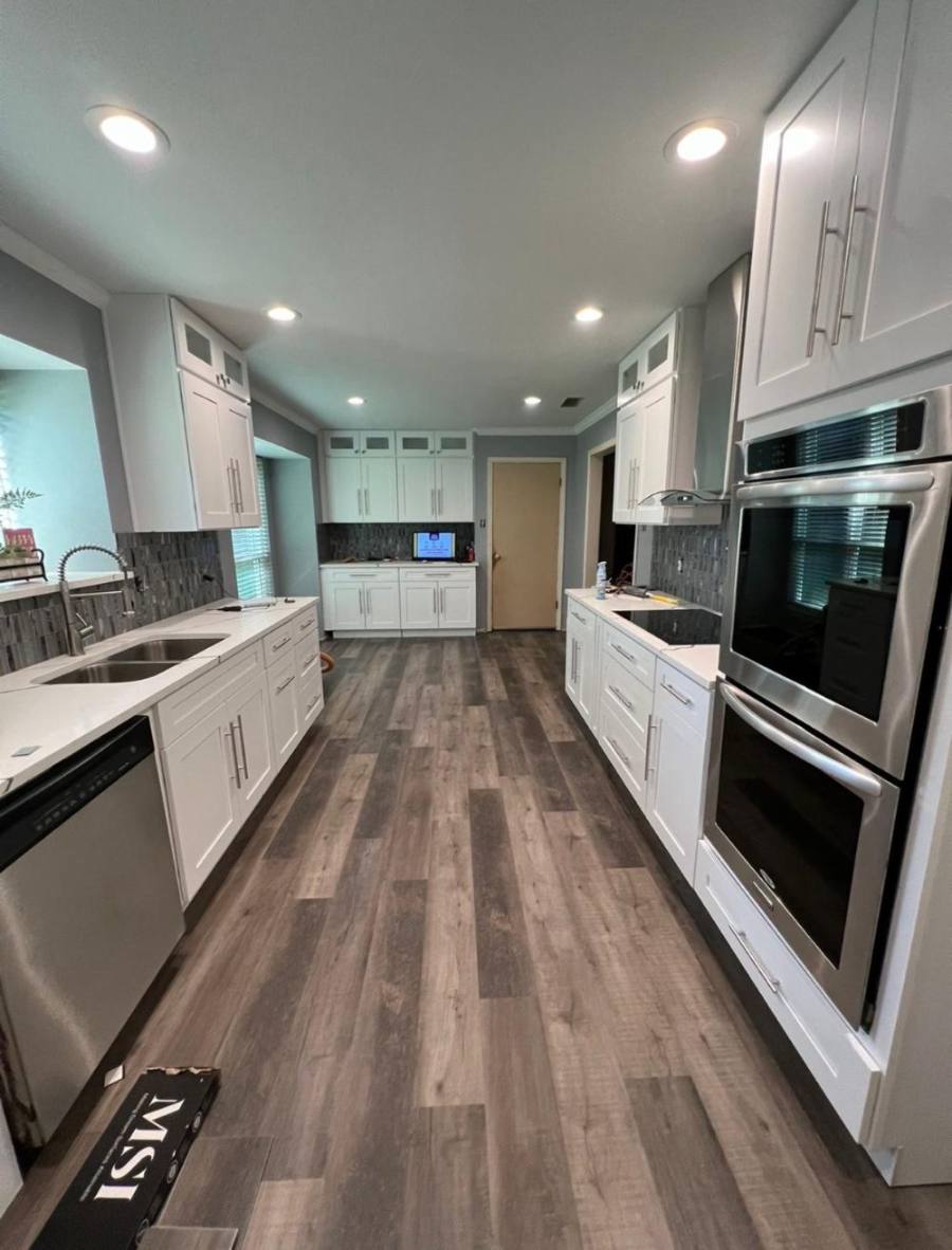 Finished kitchen with white cabinets, quartz counters and wood-look flooring